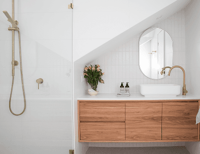Badezimmer mit einer weißen Wand, einer Dusche mit Glaskabine und einem Waschtisch aus Holz über dem ein ovaler Spiegel hängt